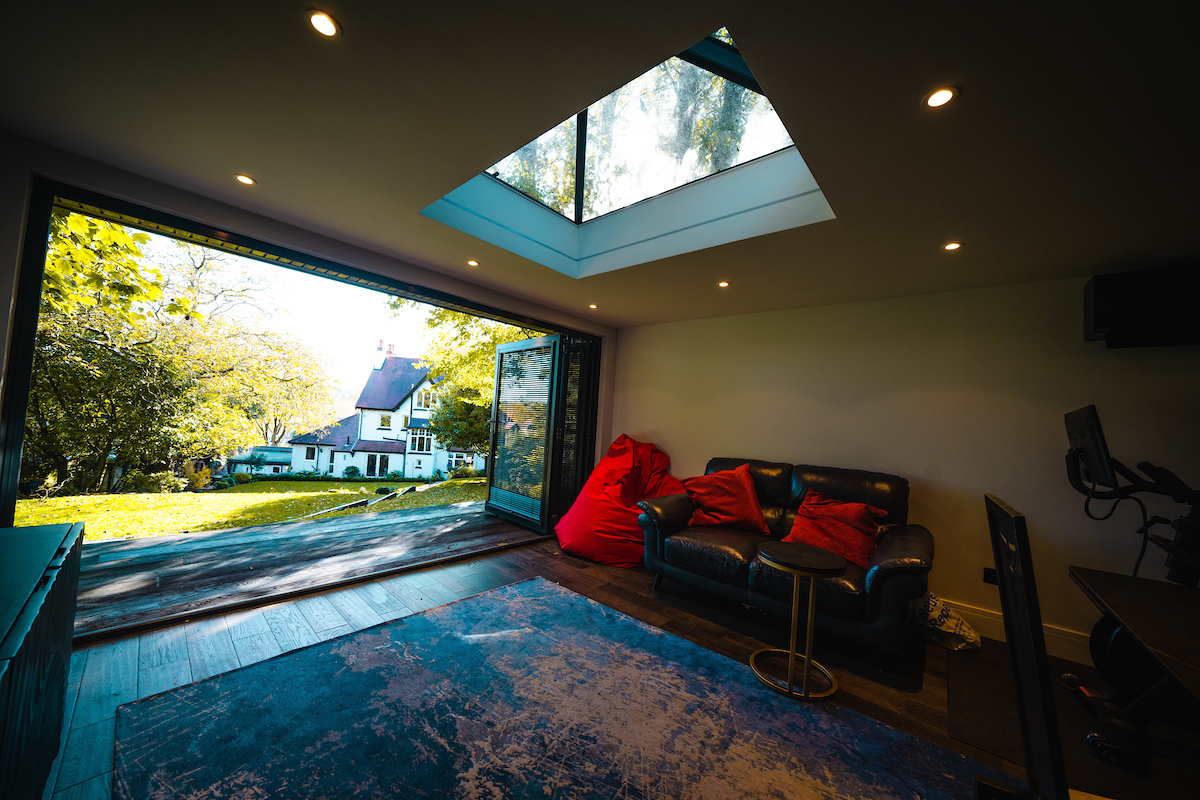 Inside of a room with a skylight and leather sofa with doors opening to a garden