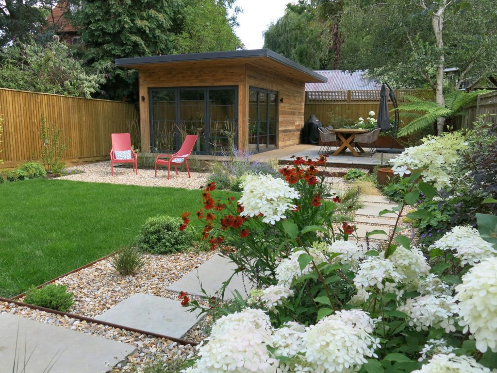 Garden building with red lounge chairs and wooden dining table