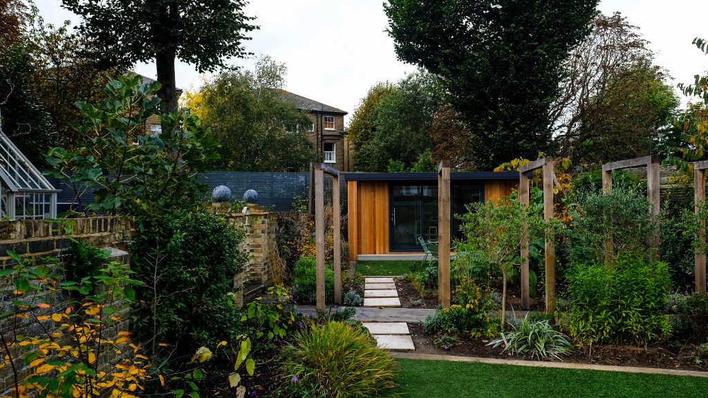 Wooden garden building seen amongst trees and greenery