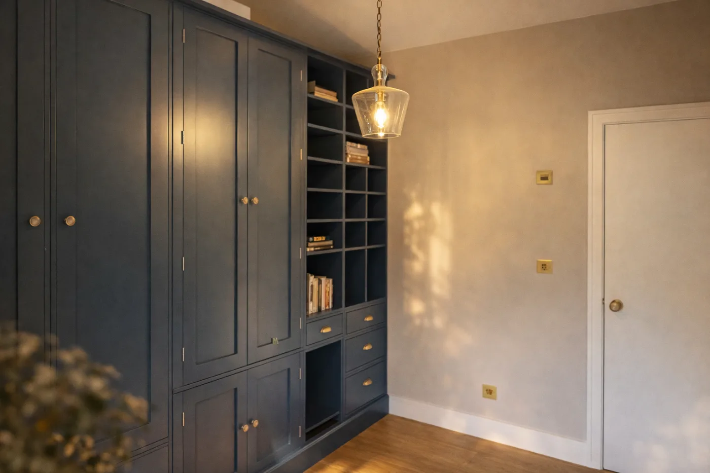 Full-height navy built-in wardrobes with open shelving in a garden room